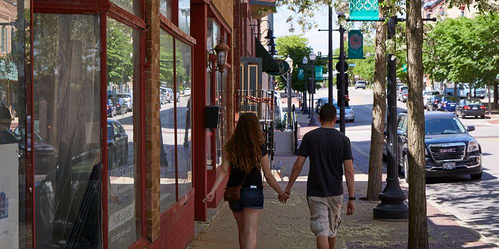 Two people walking through a suburban downtown in Kane County