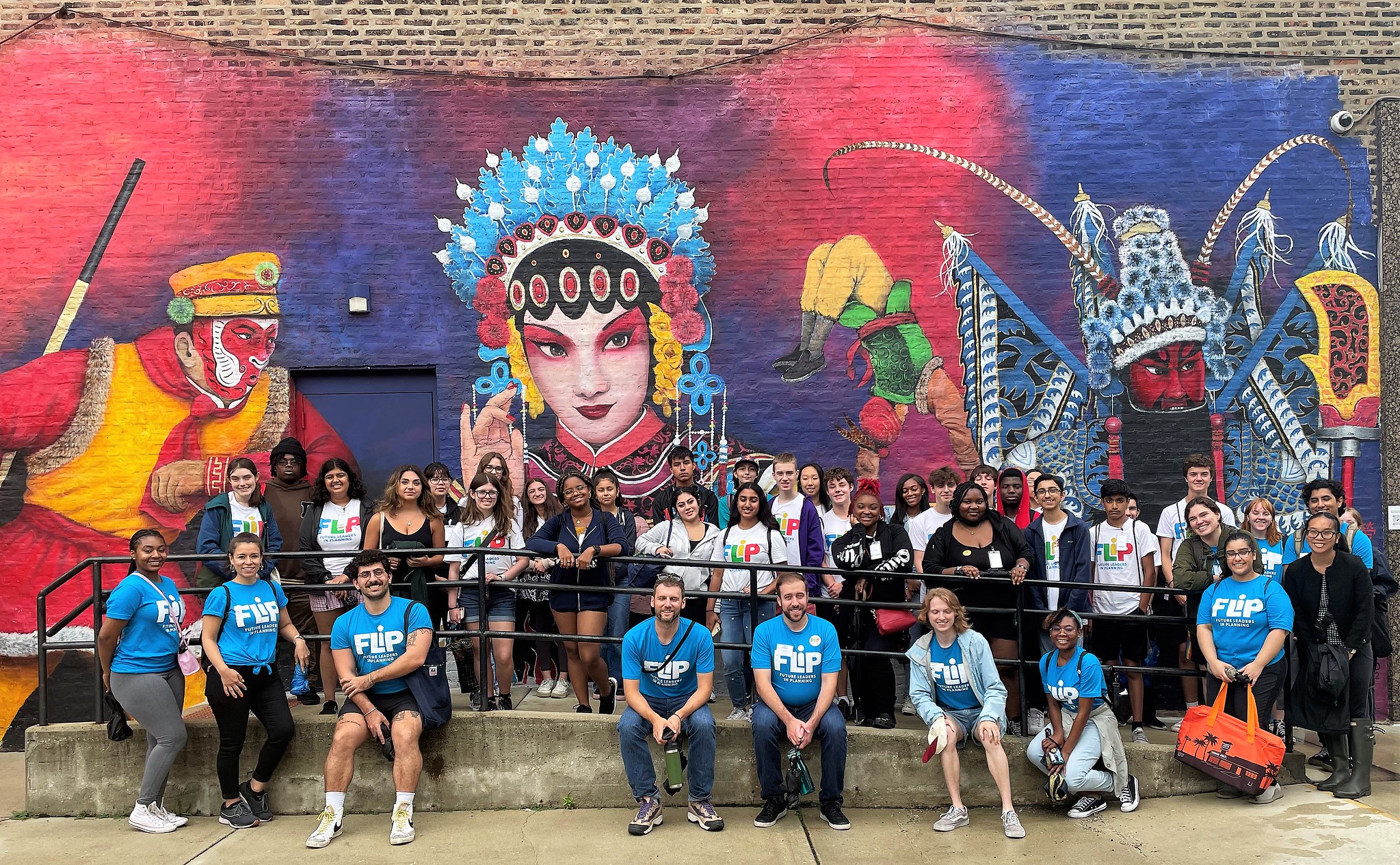 photo of a large group of FLIP students in front of a Chinatown mural with large colorful images from Chinese culture and history