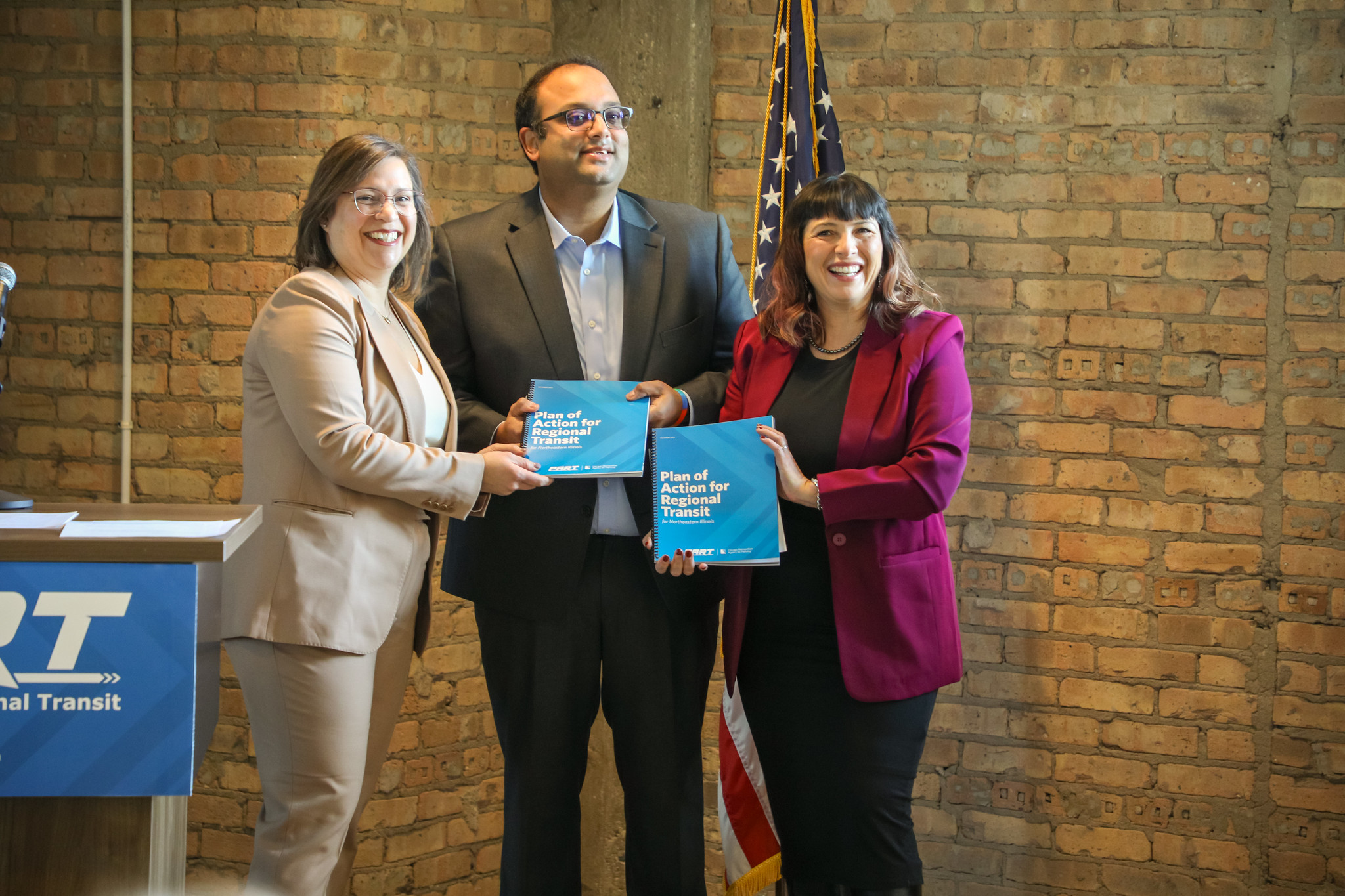 Erin Aleman, State Senator Ram Villivalam, and State Representative Eva-Dina Delgado pose with copies of the PART report